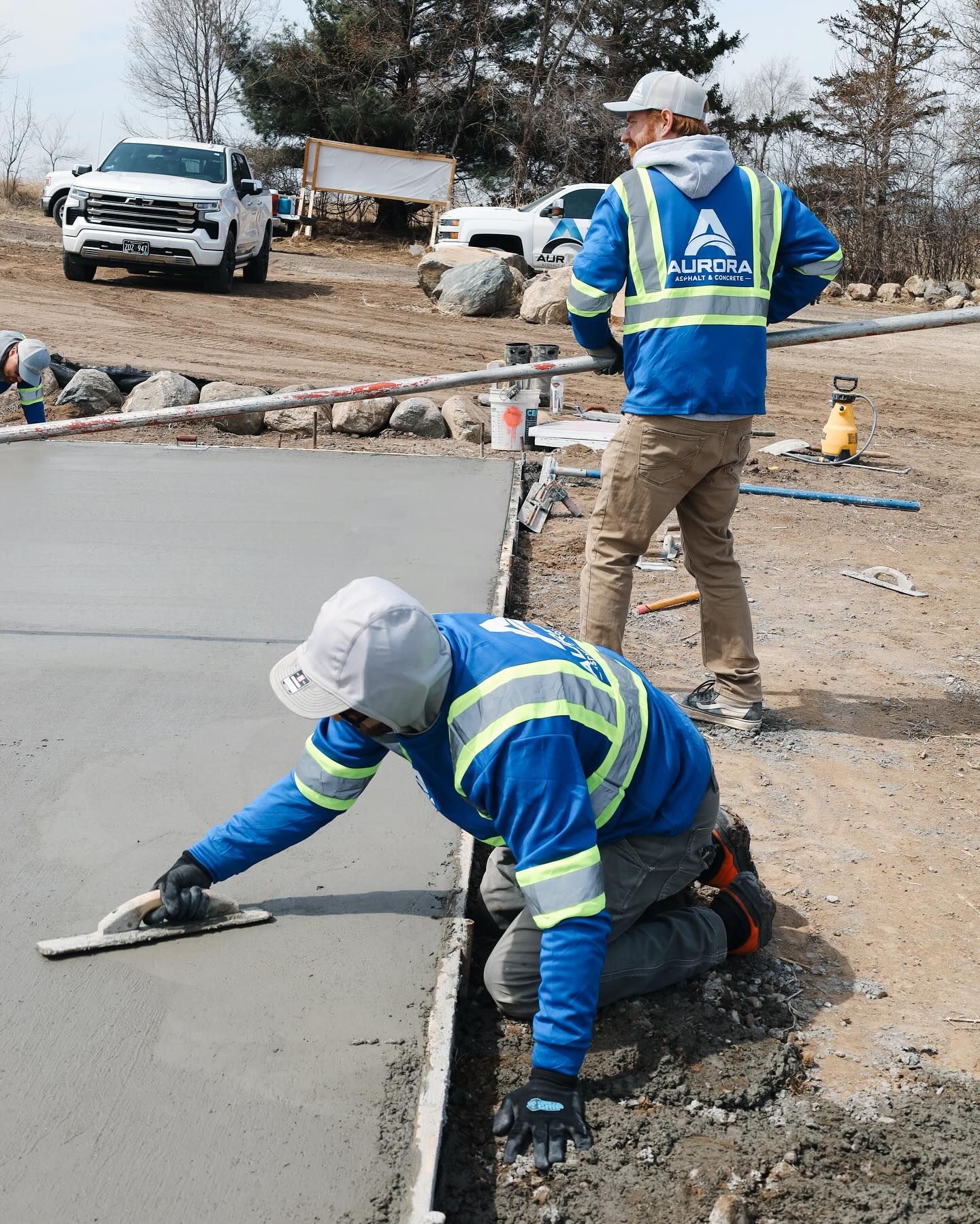 Two construction workers from Aurora Asphalt & Concrete are working on a freshly poured concrete addition in Otsego, MN.